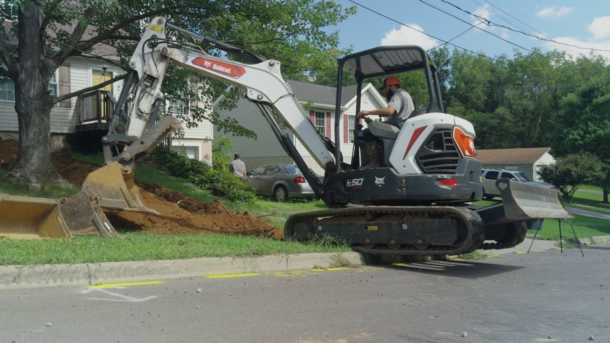 FOX excavator beside a residential lawn and a pile of excavated soil
