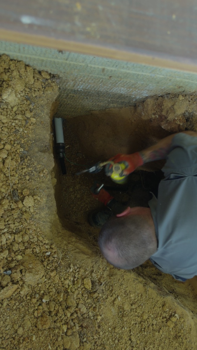 FOX technician working on a pipe connection beside the foundation
