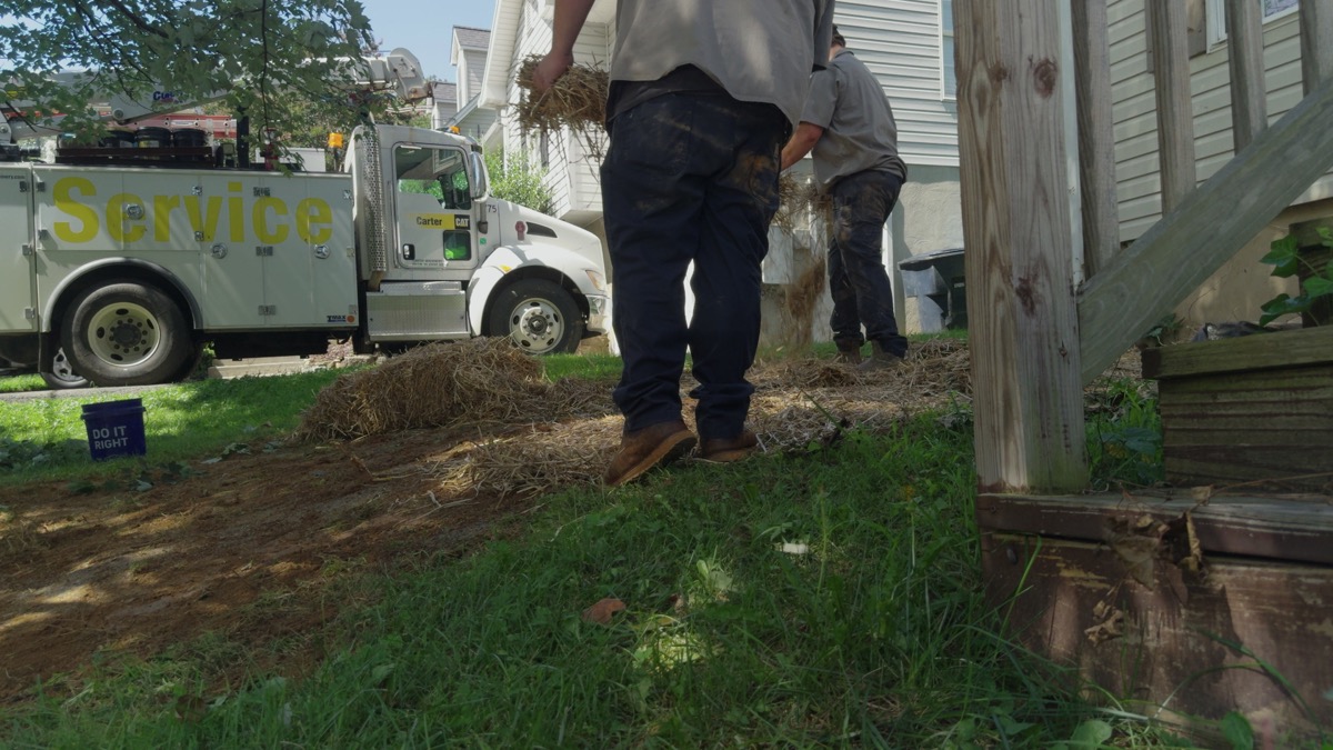FOX crew spreading straw over disturbed soil beside a house