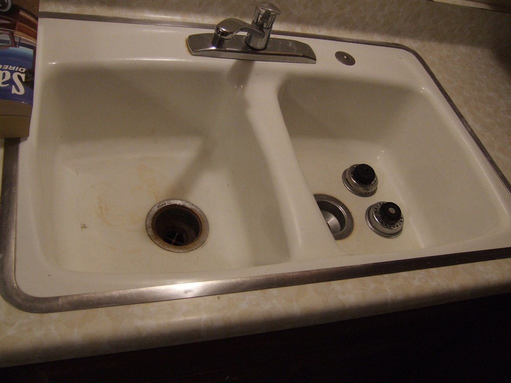 Brown-orange iron staining around a white household sink drain