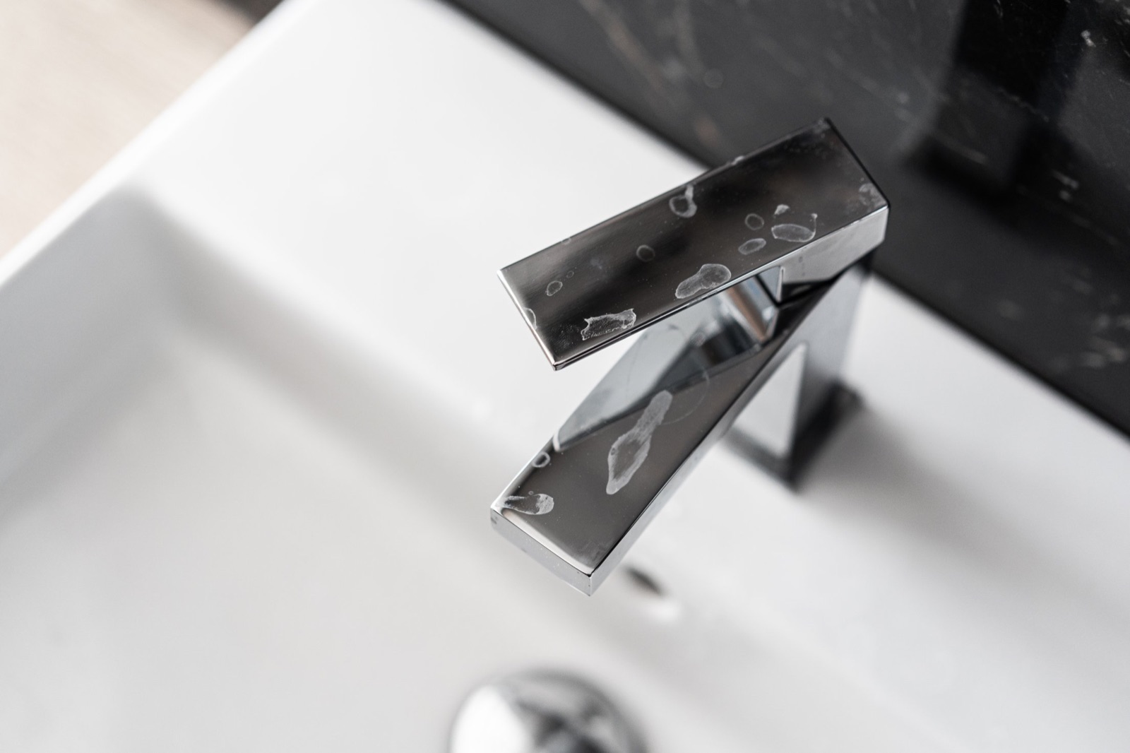 White limescale buildup around a chrome bathroom faucet